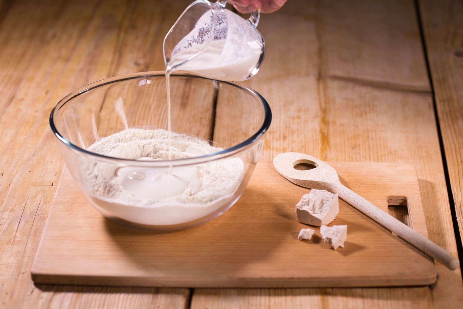 Przepis na domowe bułeczki pieczone w piekarniku: Do miski przesiać mąkę, dodać sól i zrobić wgłębienie.  Wlać do niego drożdże zakwasowe i zacząć je dodawać do mąki. 